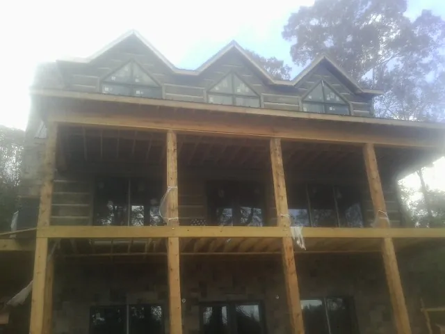 Dormers and porch framing on a large log home under construction — Roof Coating work by our crew in Criders