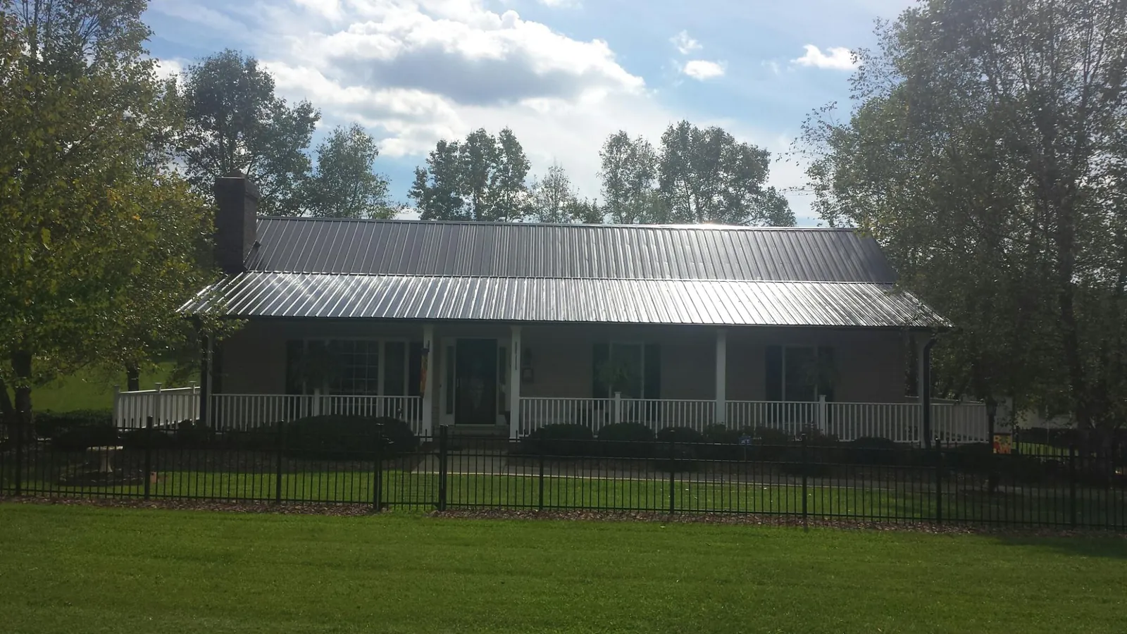 Gray metal roof on a brick ranch with a full width front porch — Gutter Guard Installation work by our crew in Criders