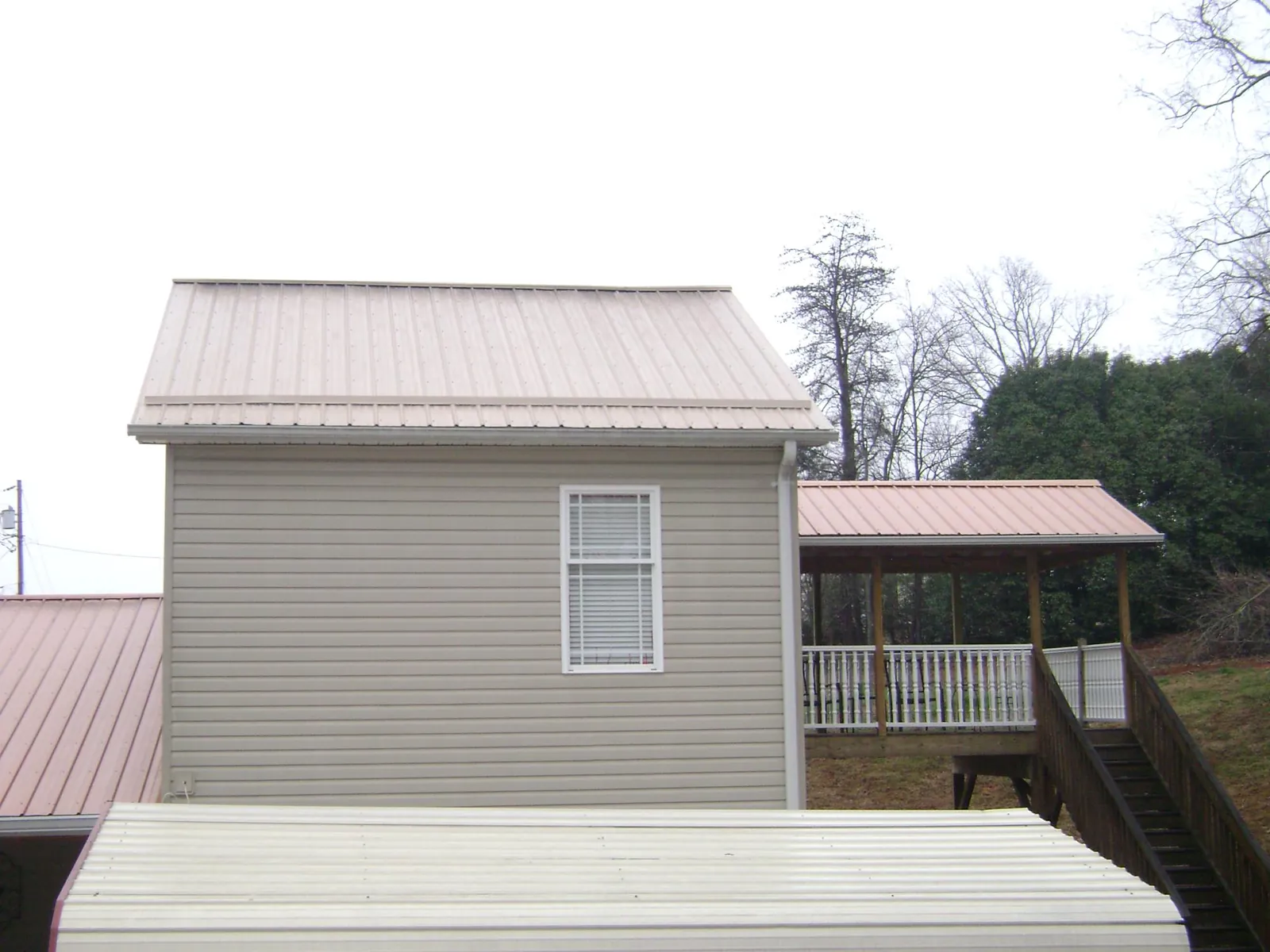 Tan metal roofs on a two story addition and attached porch, from a Roof Replacement job in Criders