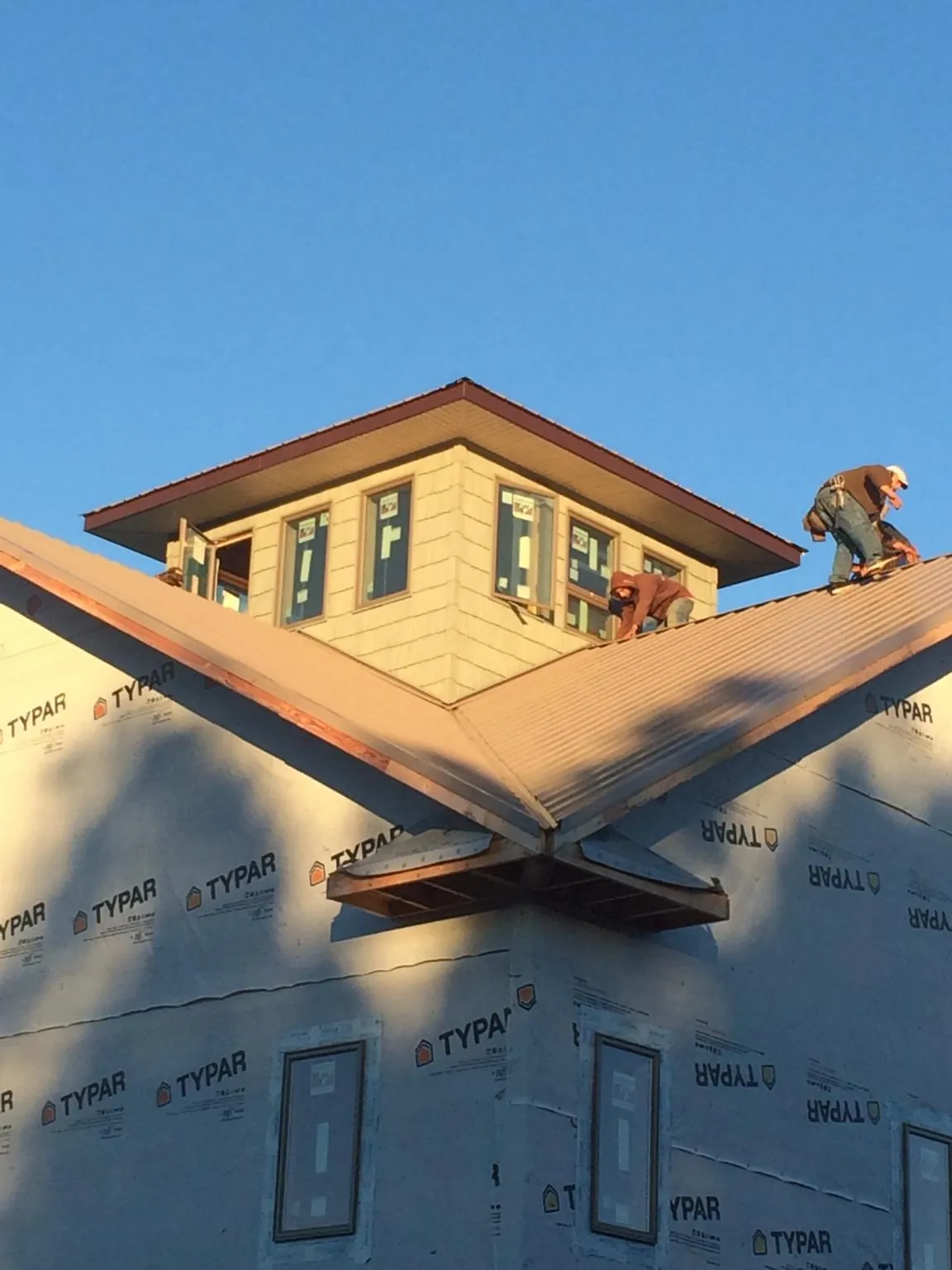 Roofers working around a rooftop cupola on a new metal roof at sunset — Roof Waterproofing in Criders by Roofing Brothers